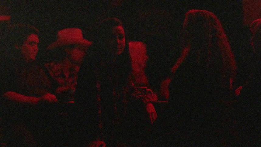Women sitting at a bar drinking alcohol with people in the background