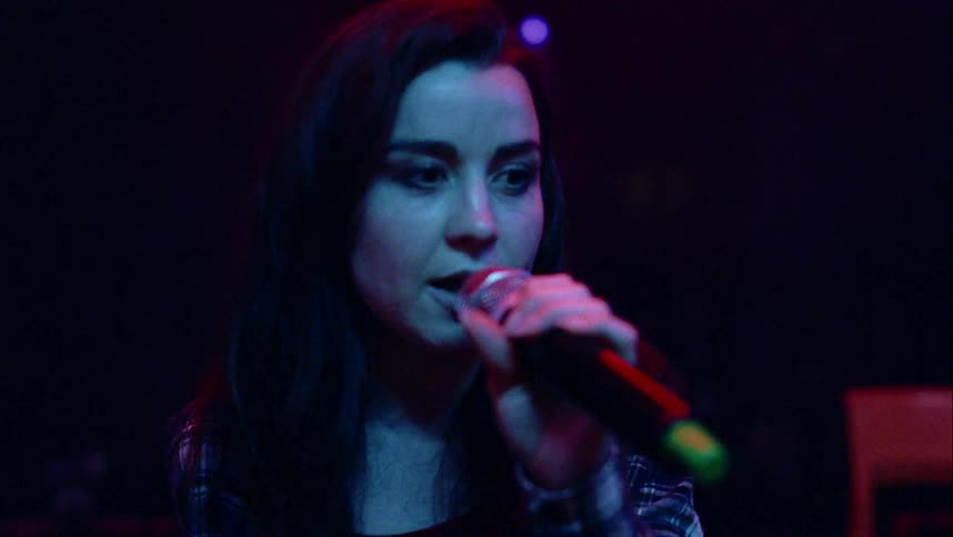Woman sings on stage holding microphone