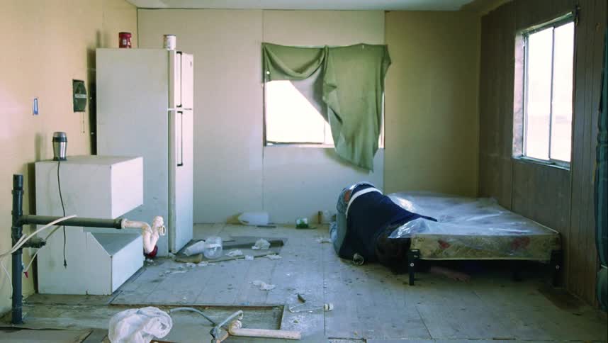 A man is searching under his bed after dropping something