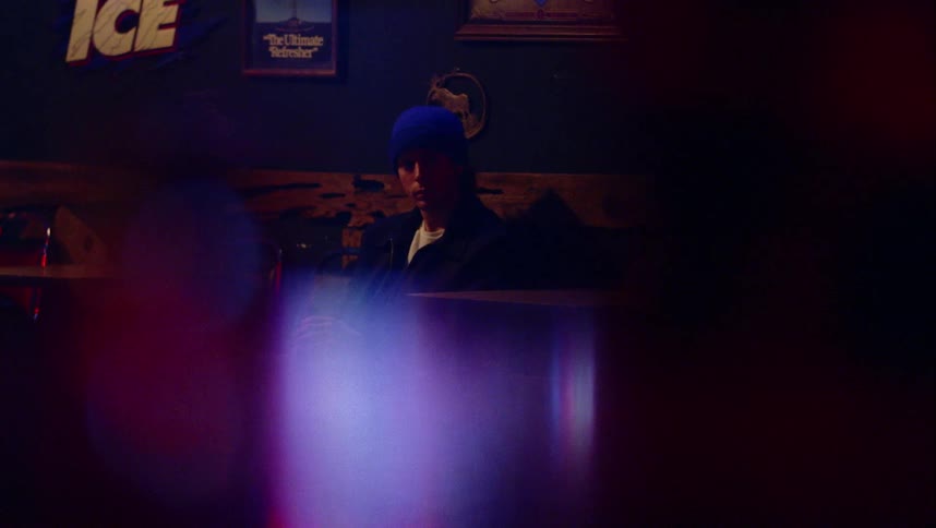 Man wearing knit hat sits in bar looking around