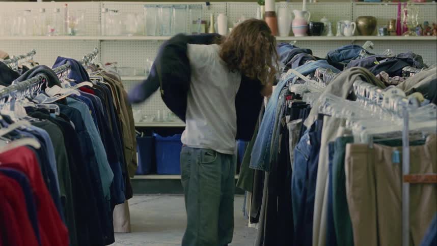 A man tries on clothing at a thrift store
