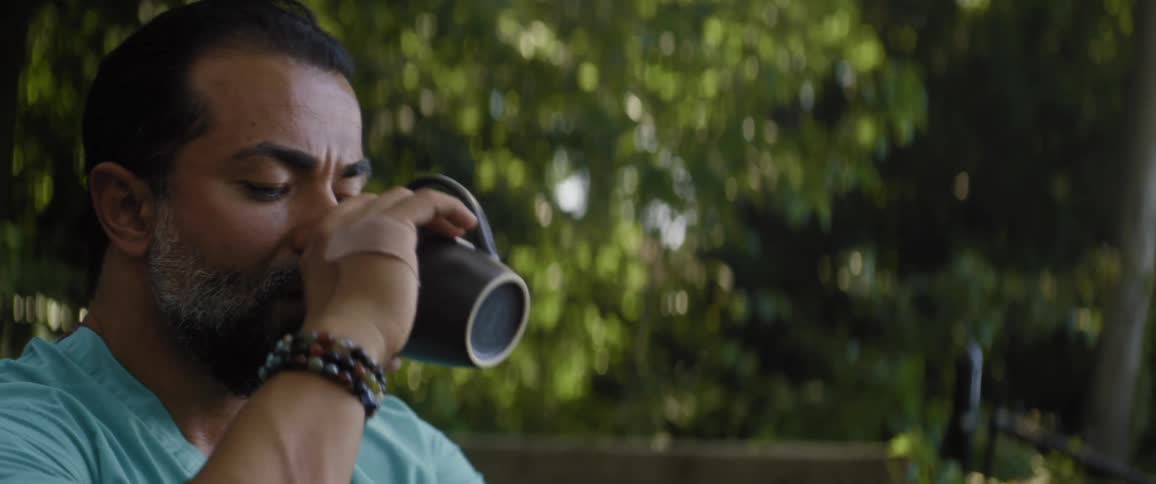 Man contemplating standing outdoors on the balcony drinking coffee