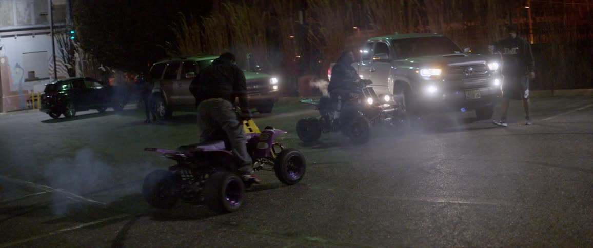 A person on a four wheeler is doing wheelies at night