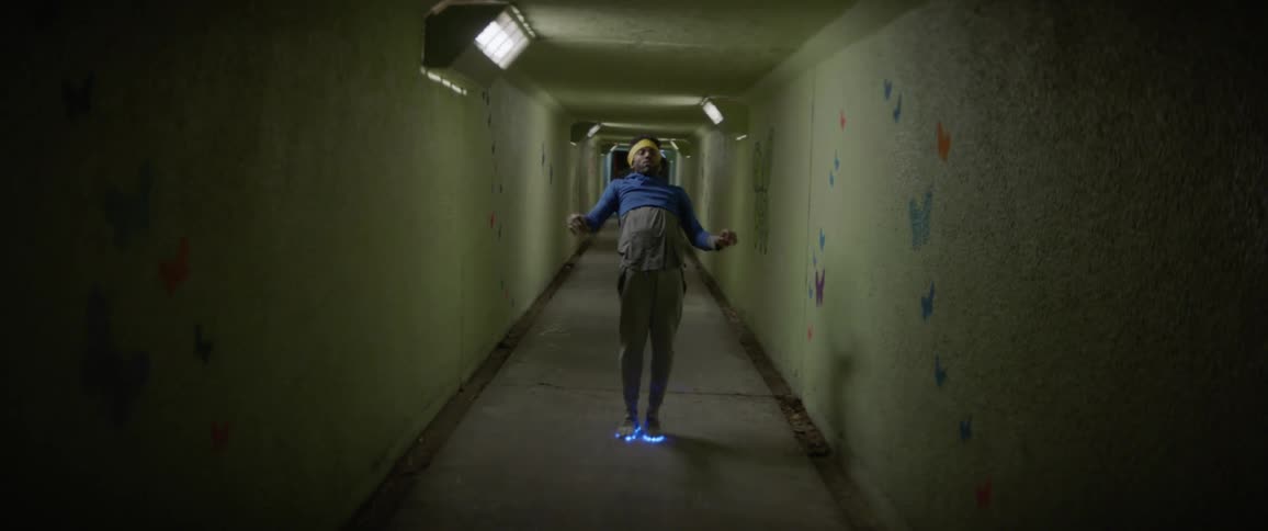 Man with neon shoes break dances in a hallway