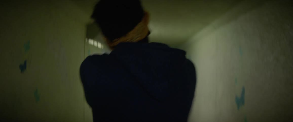 Person dances as they go down a dimly lit hallway