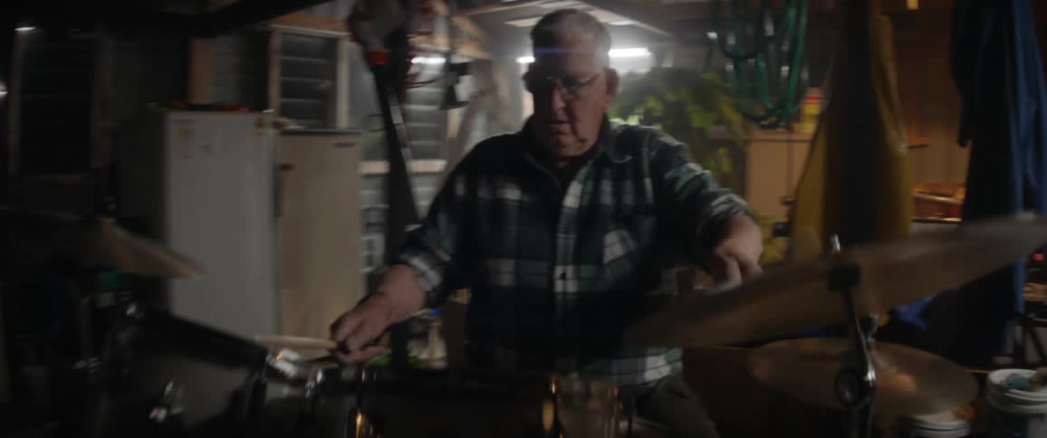 Elderly man playing drums in a garage