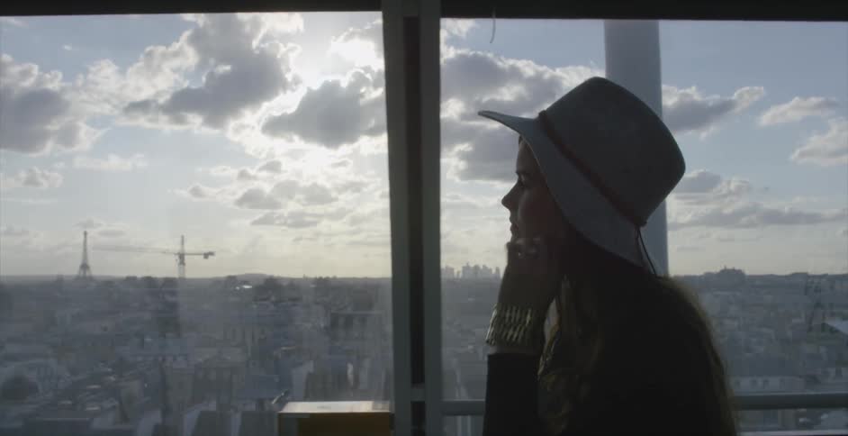 A woman wearing a floppy hat walks through a window covered walkway