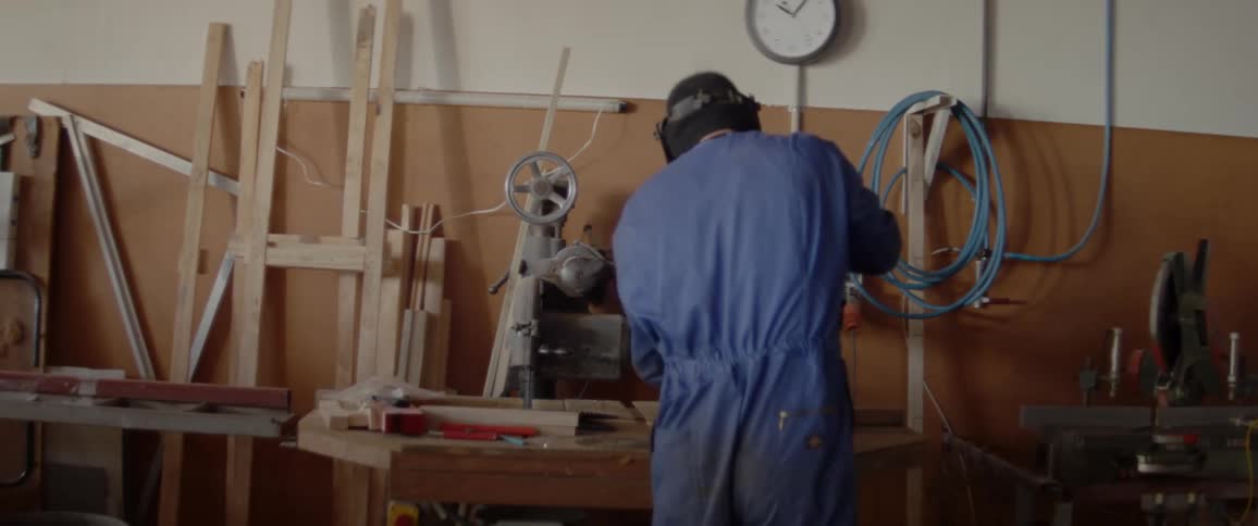 A man wears a welding mask in a workshop