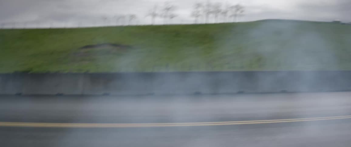 Smoke billows as a car races by