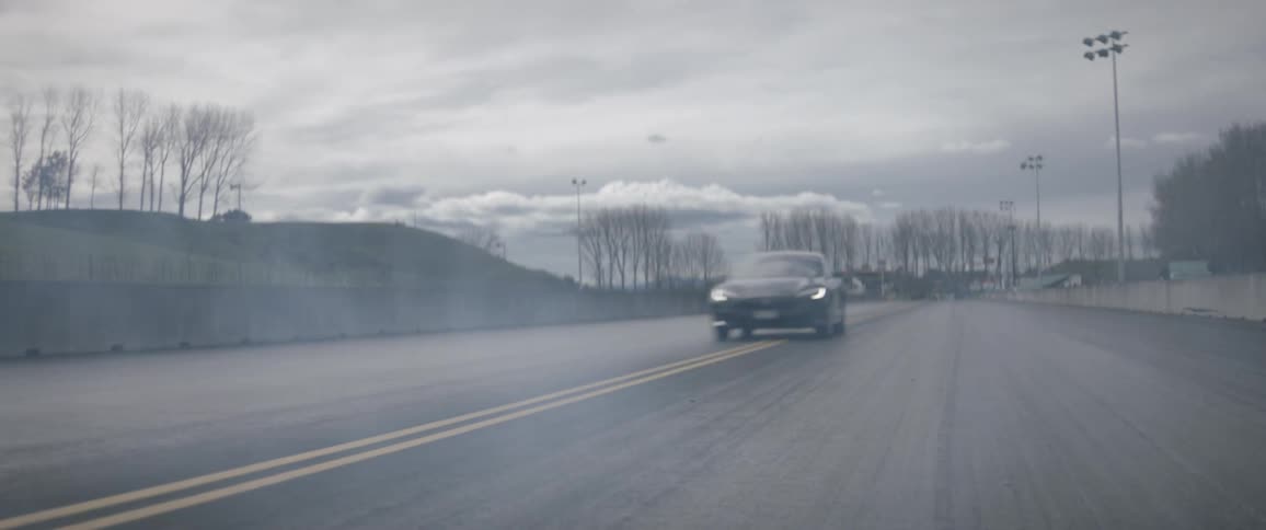 The car races down the street on a cloudy day