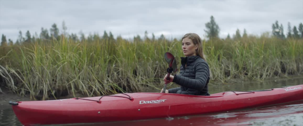 Woman paddles a kayak in a pond