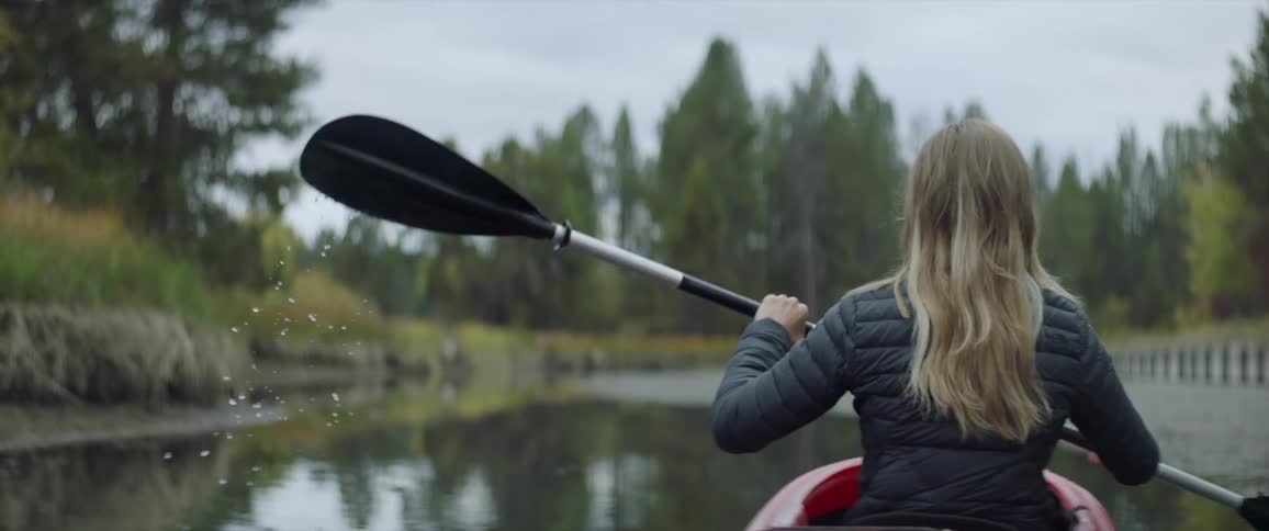 A blonde woman is paddling a kayak