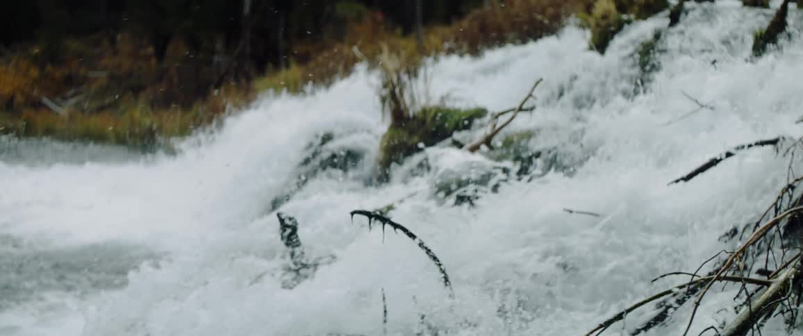 A river is splashing and rushing as it flows down a hillside during the day
