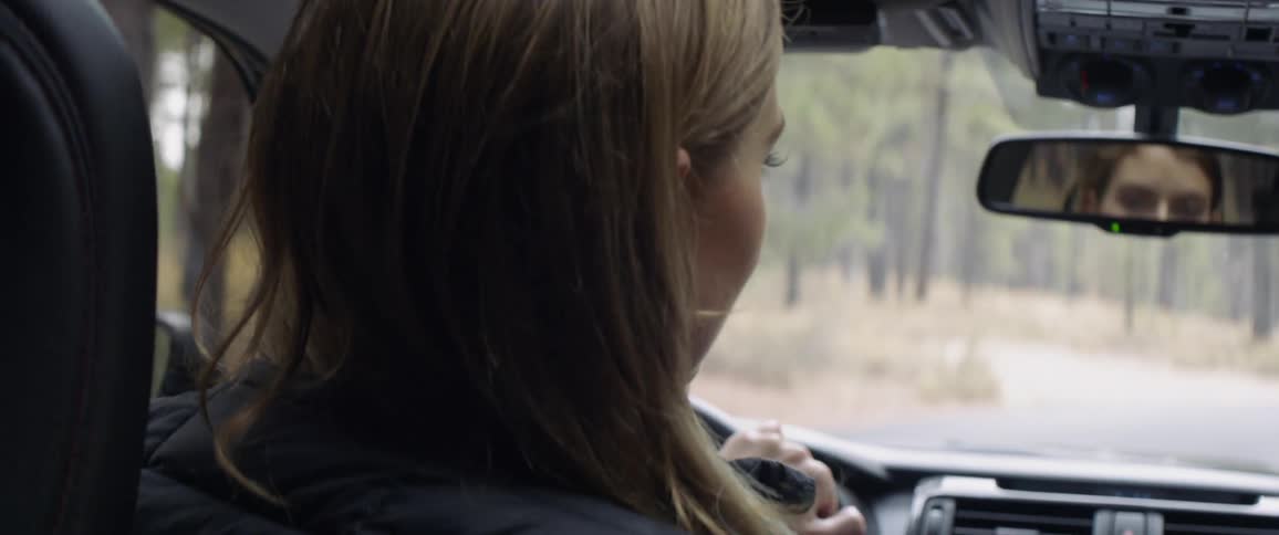 Woman drives car down a road