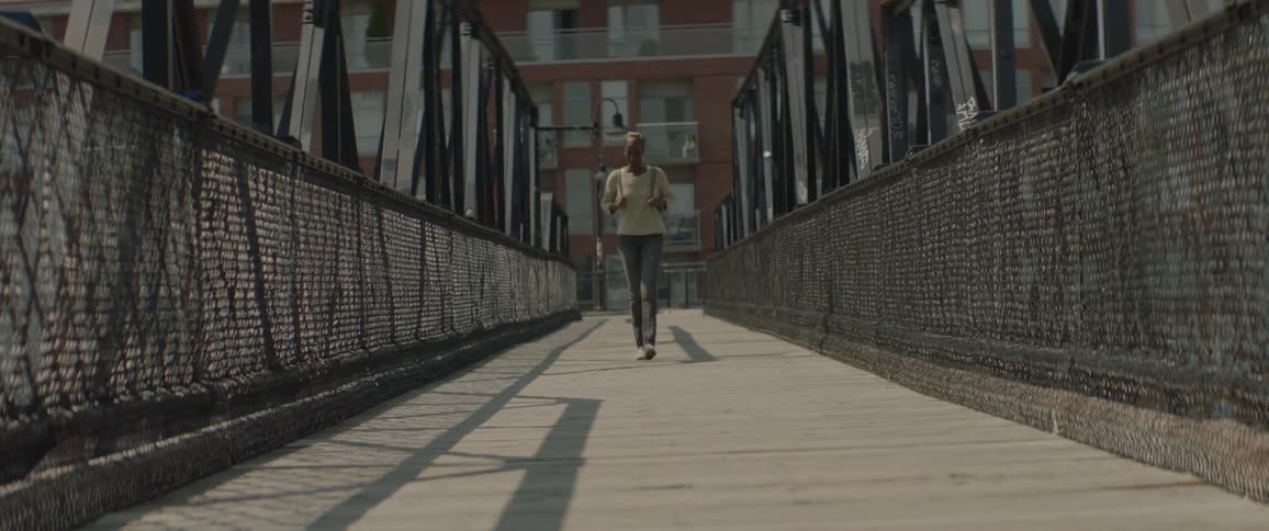 A woman is walking cross a pedestrian bridge
