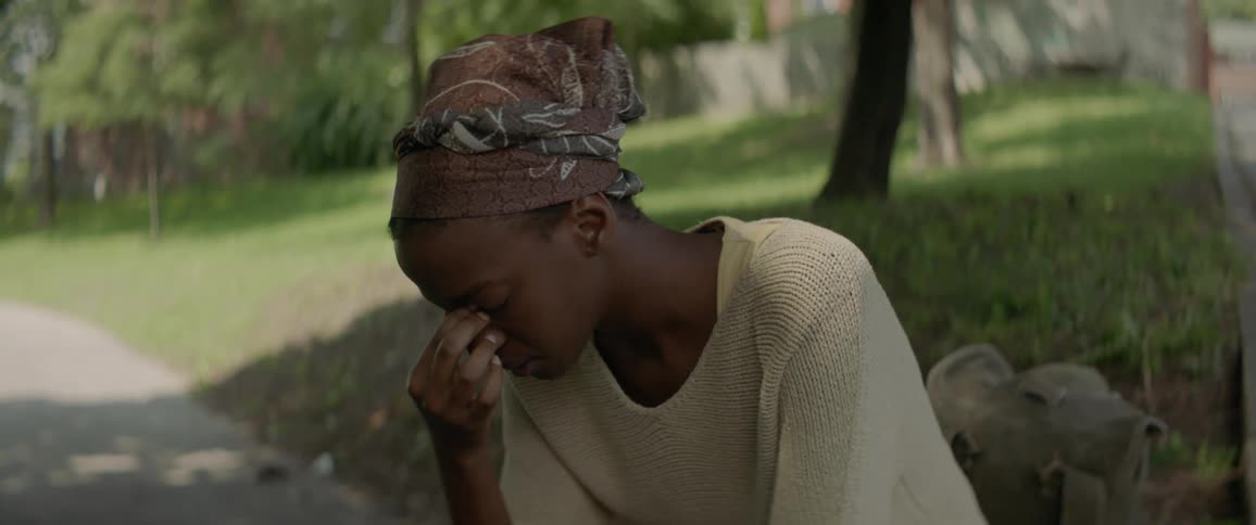 A woman is sitting on a bench rubbing her eyes during the day