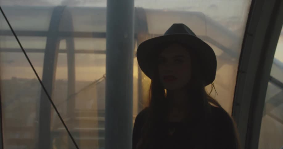 A woman is viewing a city from windows at sunset