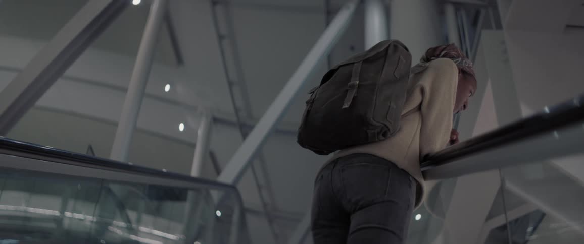 A person wearing a backpack rides an escalator