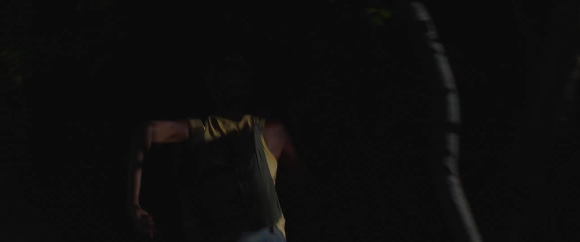 A girl wearing a backpack runs away from a car and into the trees at night