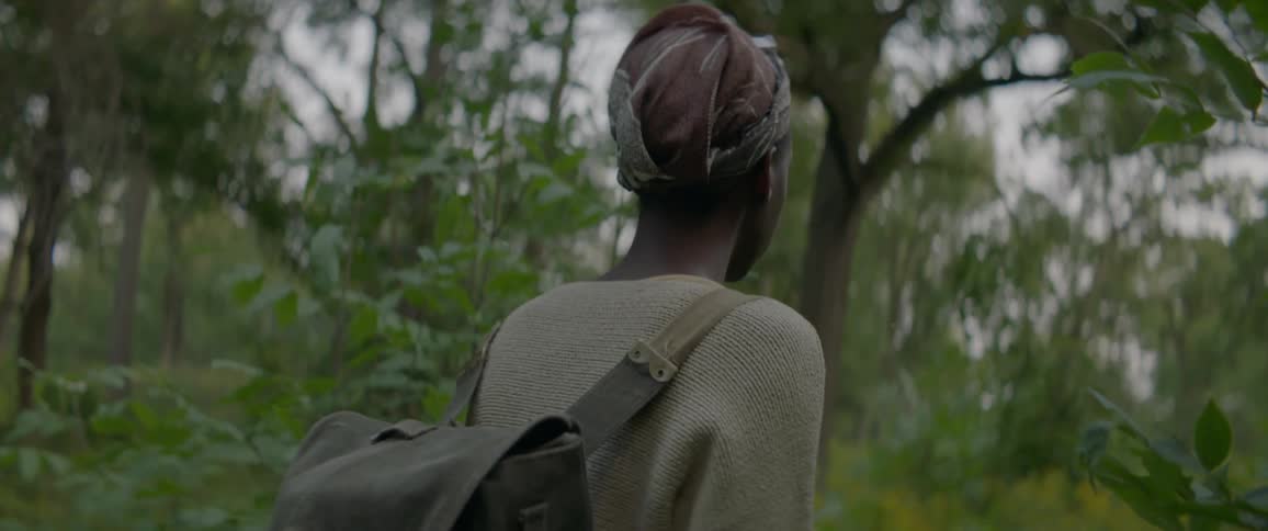 A person wearing a backpack walks through the forest