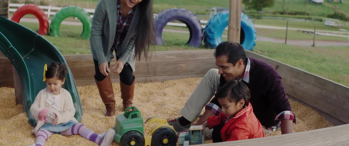 A family plays in a sandbox at a playground