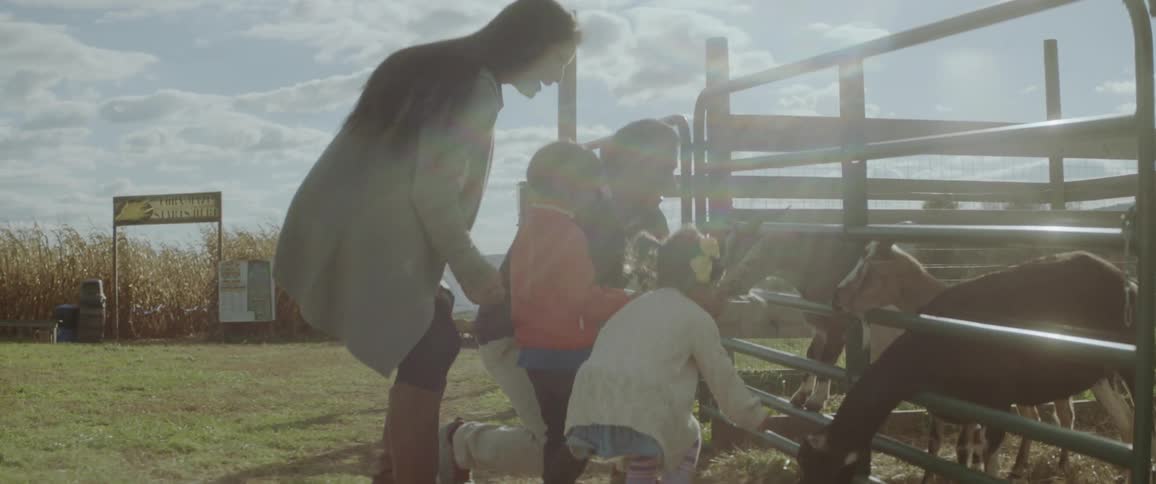 A family feeds goats on a farm
