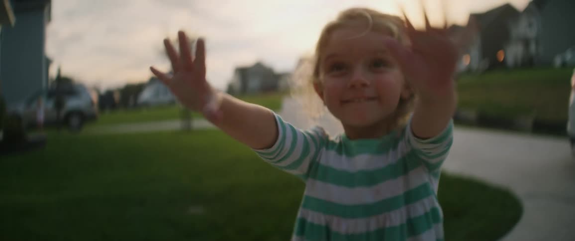 A young child has chalk on her hands after drawing on the sidewalk