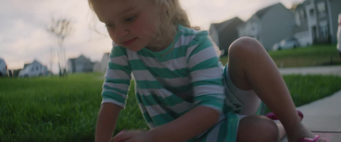 A small child is drawing on the ground with chalk