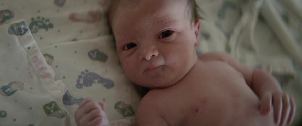 Infant blinks and waves its arms