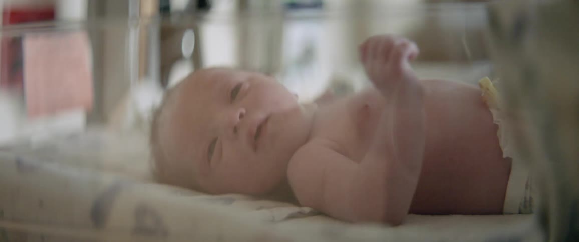 A baby is moving its arms as it lays in a crib in daylight