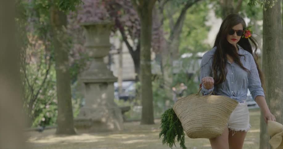 A woman carrying a shopping bag as she walks through an urban park