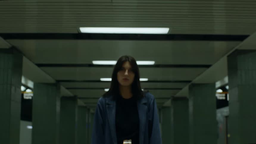 A woman is standing in the middle of the subway platform