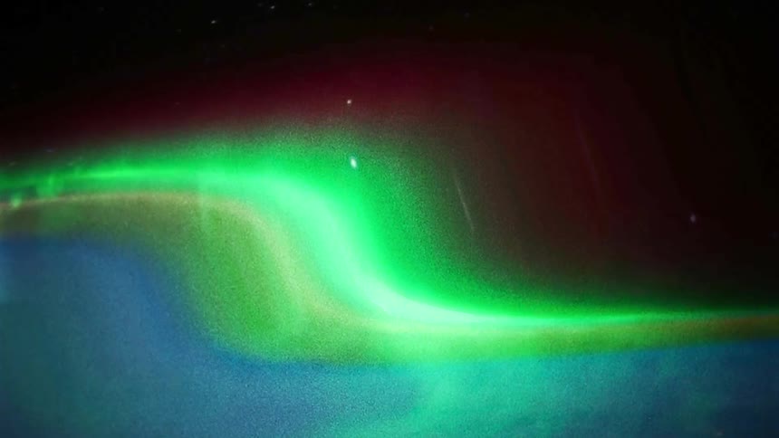 A glowing distorted bluegreen spectrum moving in a wavelike motion against a dark background