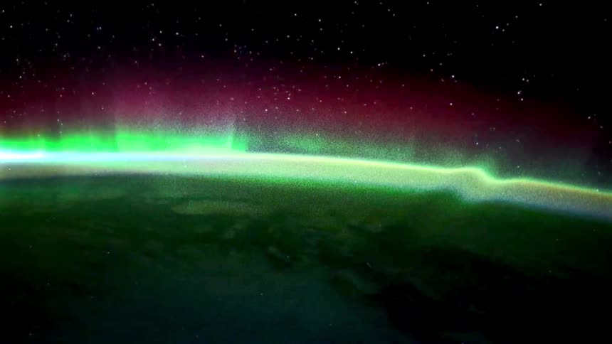 From high above the earth and in outer space the beautiful green glow of the aurora borealis can be see shining high in the atmosphere