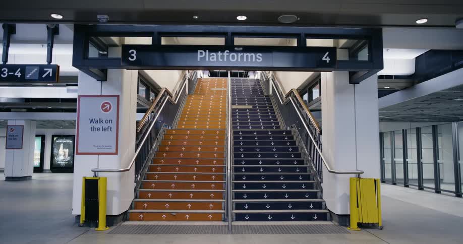 A train station with a staircase signs and pillars