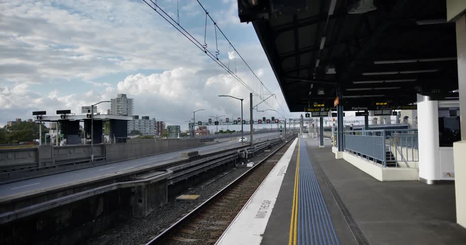 Several automobiles drive along a freeway next to an empty train station platform