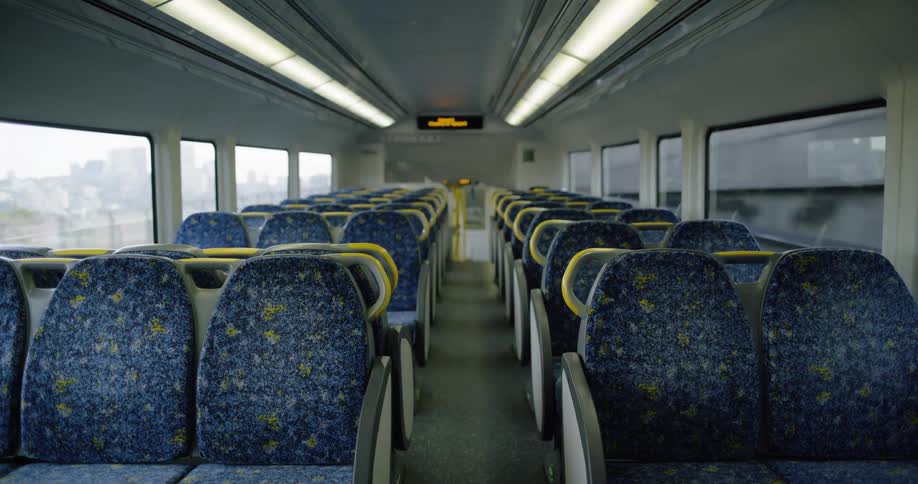 Empty public transportation car moves along with city skyline visible through windows