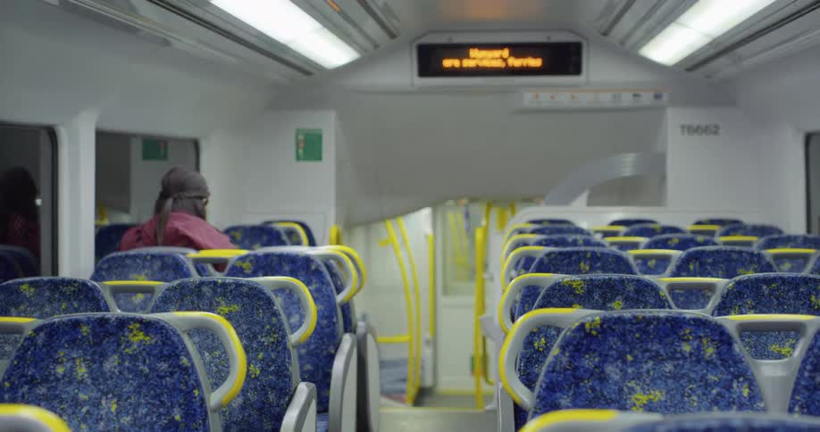 A lone passenger sits in a swaying transit train car as the train is in motion