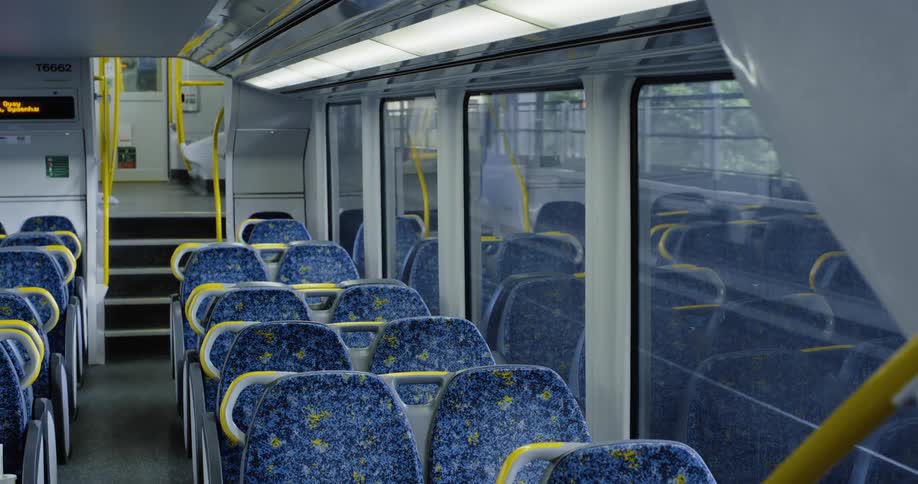 An empty train moving on a train track with the train platform outside the window