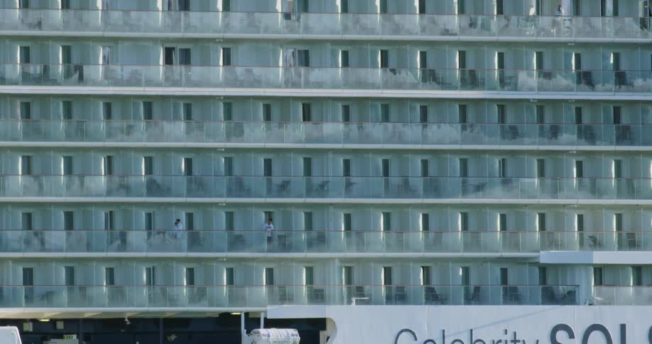 People on different floors relax on the balconies of a large residential building