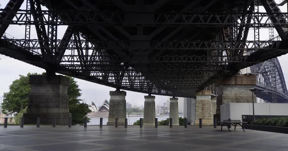 The sydney harbour bridge crosses the water and leads to the sydney opera house