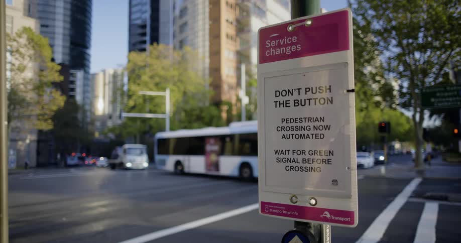 A sign notifying pedestrians about an automatic crossing signal at an intersection in a metropolis during the day