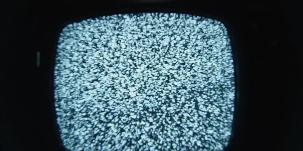 Rapidly nearing and retreating from old television showing static signal in shadowy empty room