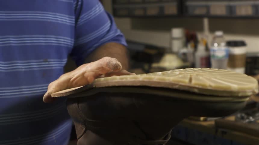 A man hammers a sole onto a boot