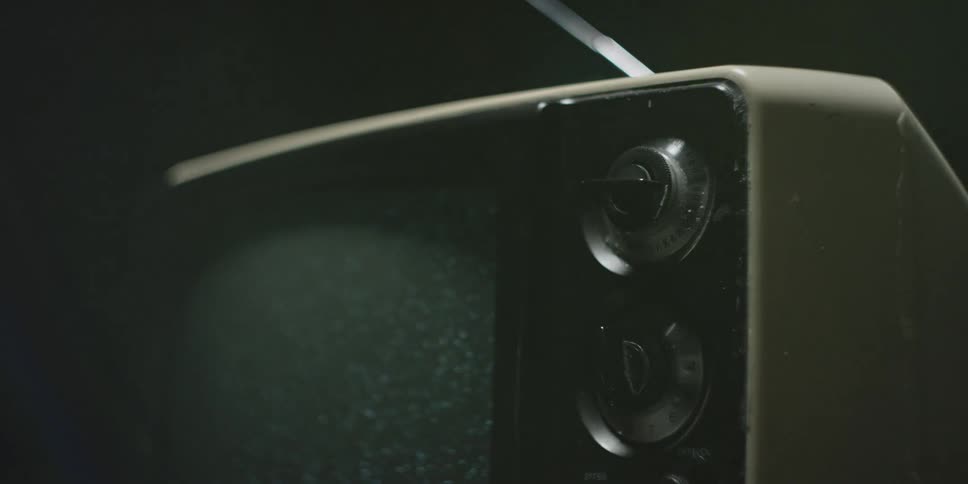An old television set displays static in the dark