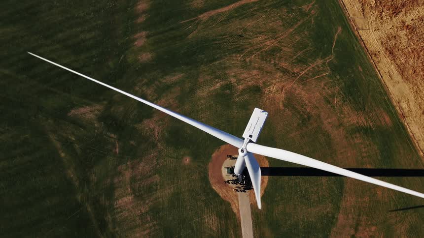 A spinning wind turbine in a field doing the day