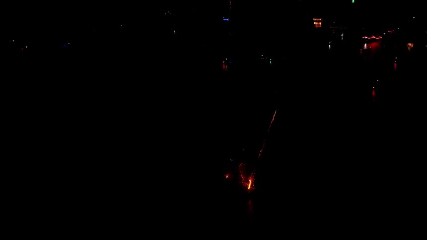 Fireworks explode in a dark night sky in a city