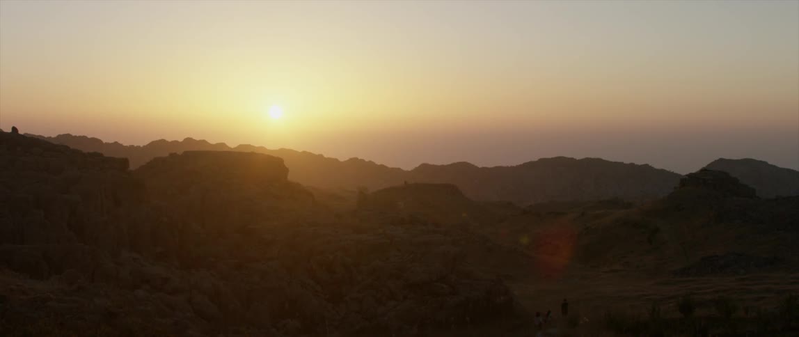The sun is setting in the distance behind some mountains