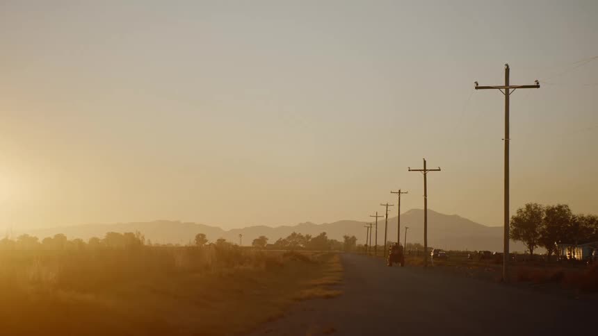 A vehicle driving down a road in a rural area