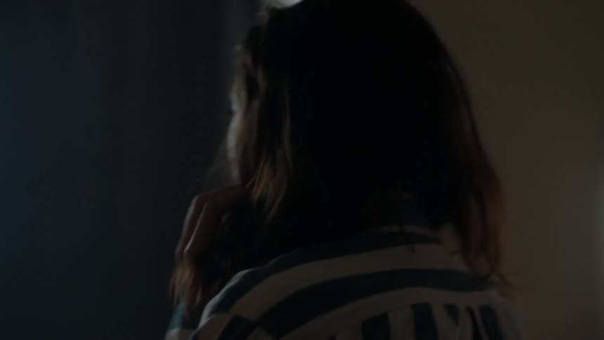 A woman is upset, pacing around a house.
